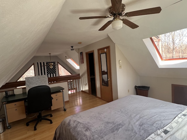 bedroom featuring lofted ceiling with skylight, light wood finished floors, and a textured ceiling