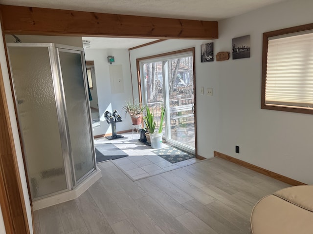 doorway to outside with beamed ceiling, light wood-style flooring, and baseboards