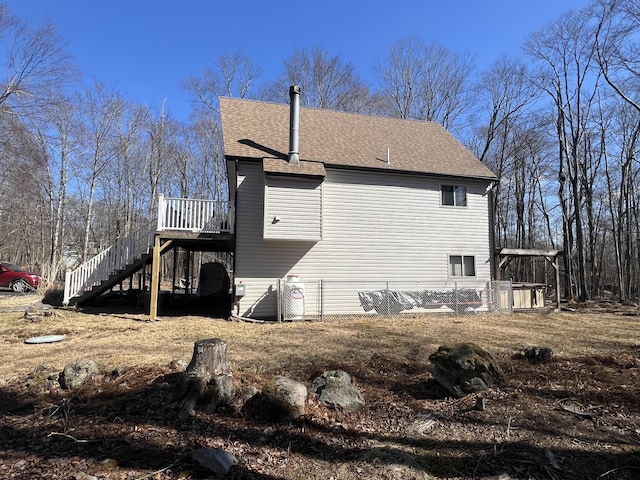 view of side of property featuring a deck, stairs, and a shingled roof