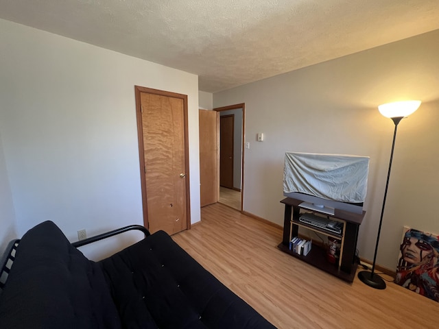 bedroom featuring baseboards, a textured ceiling, and wood finished floors