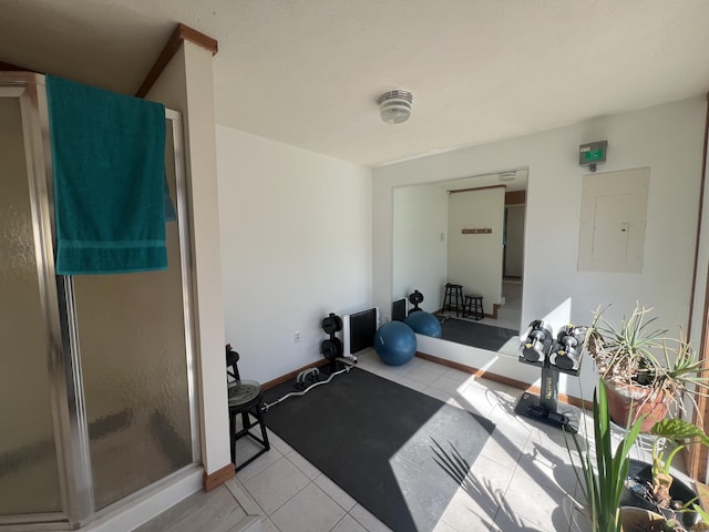 exercise area featuring electric panel, baseboards, and light tile patterned flooring