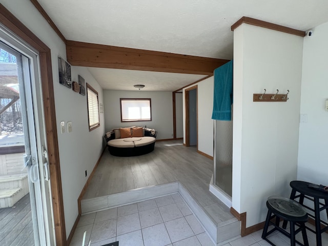 hallway with light tile patterned flooring, beamed ceiling, and baseboards