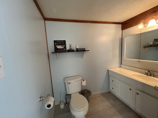 bathroom with toilet, vanity, and baseboards