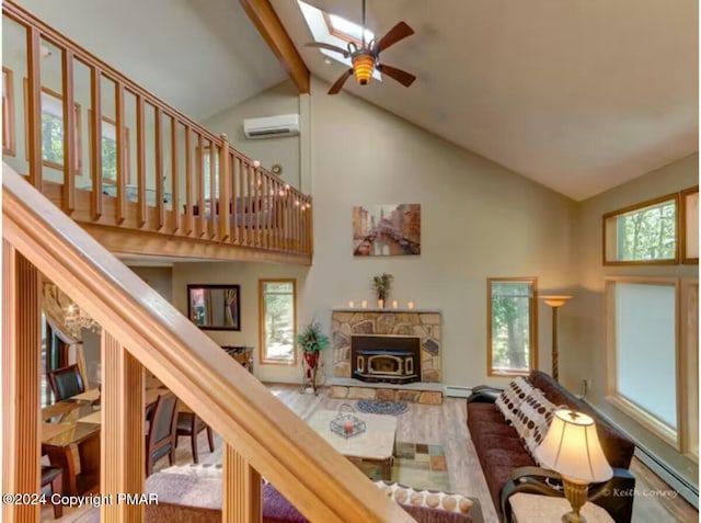 living area with a skylight, beamed ceiling, a wall mounted air conditioner, baseboard heating, and high vaulted ceiling