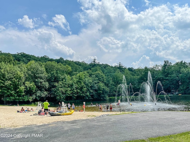 view of play area with a water view and a view of trees