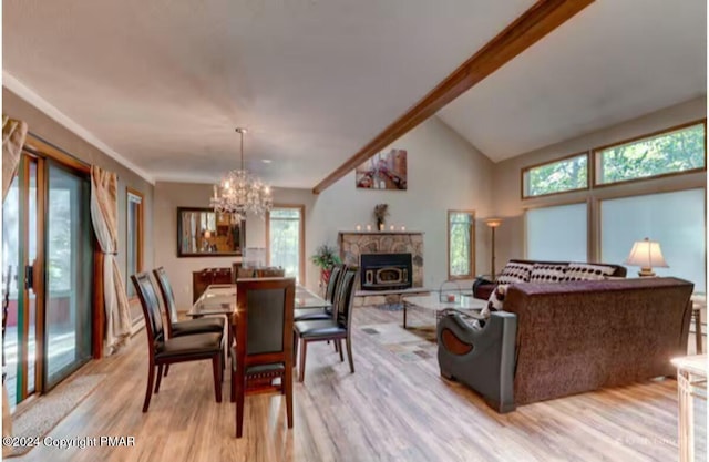 dining area featuring a chandelier, high vaulted ceiling, a stone fireplace, and light wood finished floors