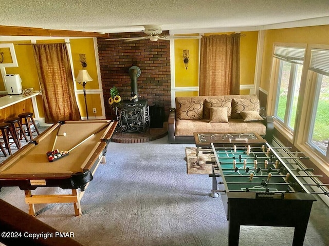 recreation room with a textured ceiling, carpet flooring, billiards, and a wood stove