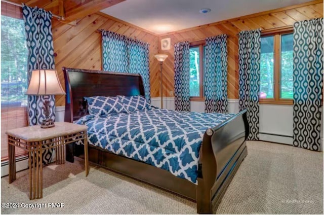 carpeted bedroom with wood walls, multiple windows, and a baseboard radiator