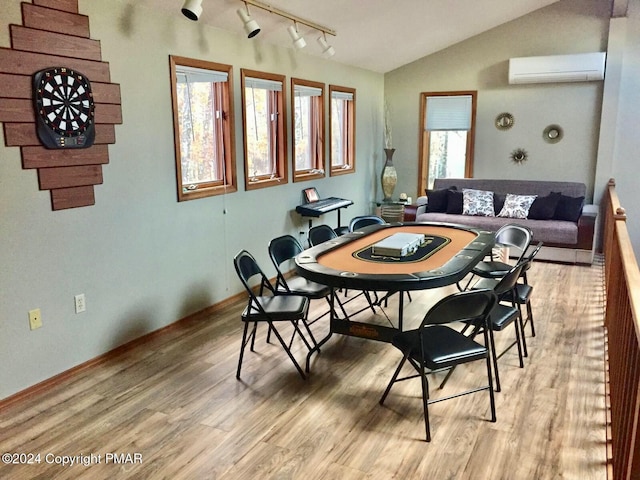 dining room with baseboards, vaulted ceiling, light wood finished floors, a wall mounted air conditioner, and rail lighting