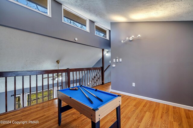 game room featuring billiards, wood-type flooring, a textured ceiling, and plenty of natural light