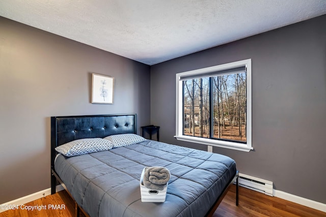 bedroom with hardwood / wood-style flooring, a baseboard radiator, and a textured ceiling