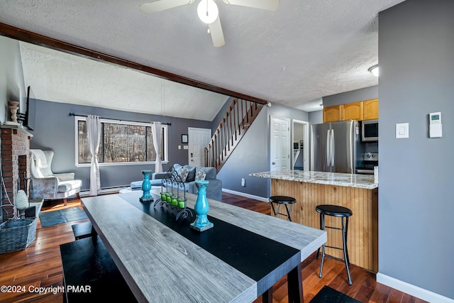 interior space with ceiling fan, dark hardwood / wood-style floors, a brick fireplace, and a textured ceiling