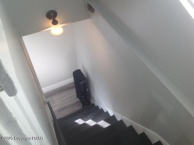 stairway with wood-type flooring and radiator heating unit