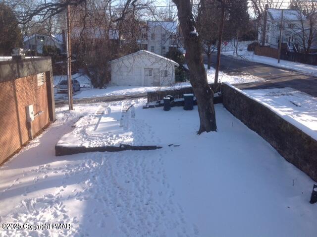 yard layered in snow with an outbuilding