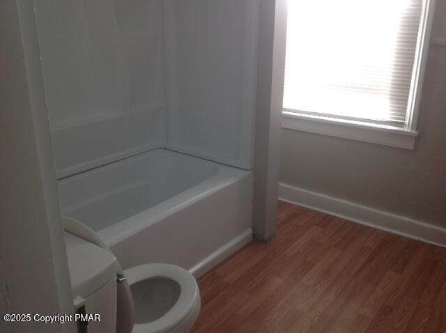 bathroom with toilet, baseboards, and wood finished floors