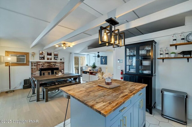 kitchen with butcher block counters, a wall mounted AC, a kitchen island, a chandelier, and beamed ceiling