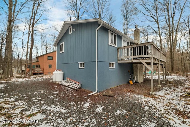 snow covered property with a deck and a chimney