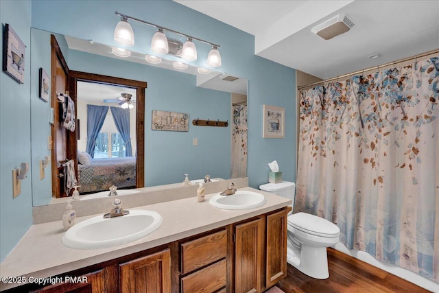 ensuite bathroom featuring double vanity, wood finished floors, a sink, and toilet