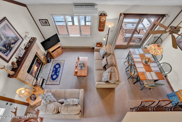 living area featuring baseboard heating, a wall mounted air conditioner, and a glass covered fireplace