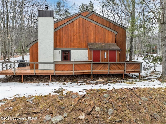 snow covered house with a deck and a chimney