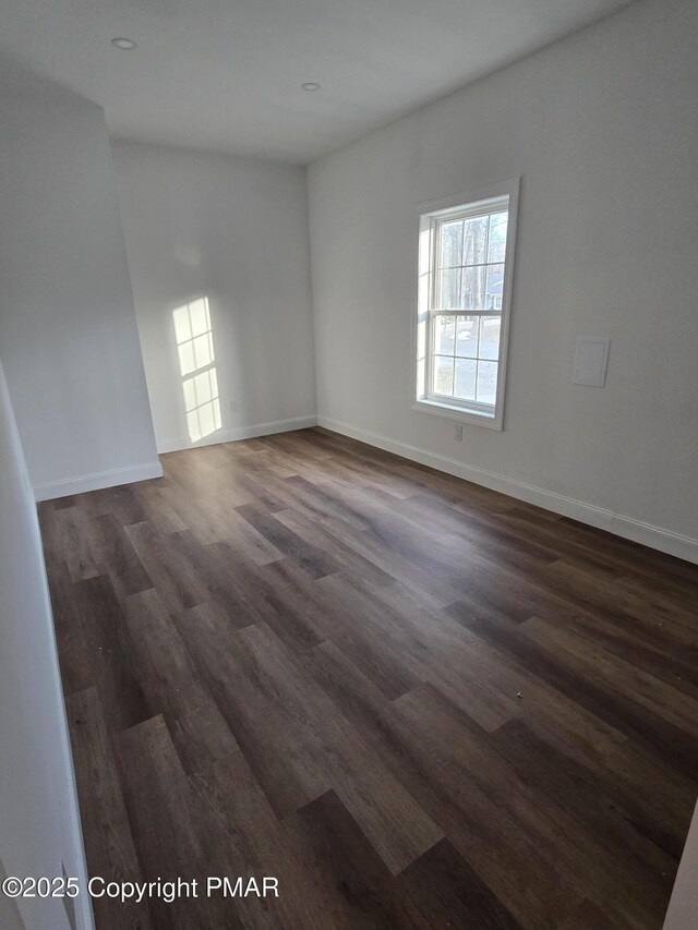 spare room featuring dark wood-style floors and baseboards