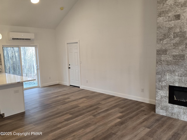 unfurnished living room featuring dark wood finished floors, high vaulted ceiling, a wall mounted air conditioner, and baseboards