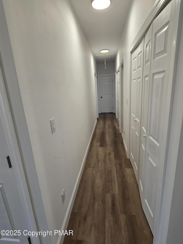 hall featuring attic access, dark wood-style floors, and baseboards