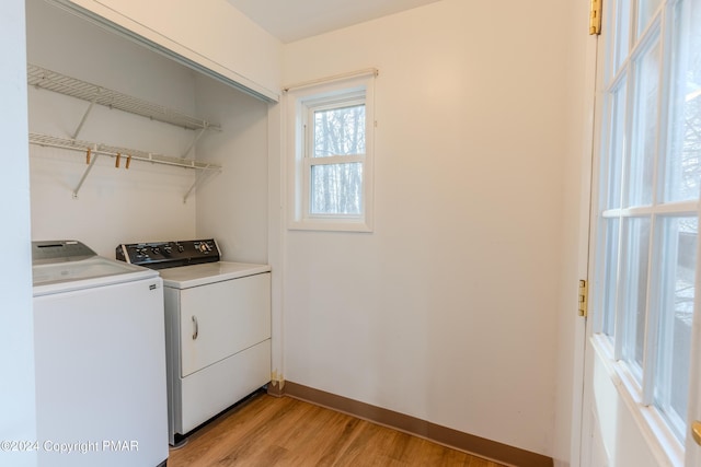 clothes washing area featuring light wood-style floors, baseboards, laundry area, and washer and dryer