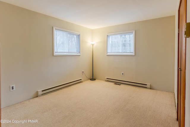 carpeted spare room with a baseboard heating unit and a healthy amount of sunlight