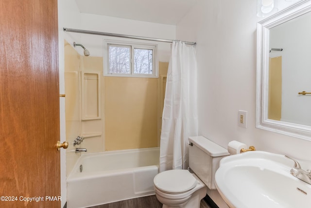 bathroom with toilet, shower / bath combo, and a sink