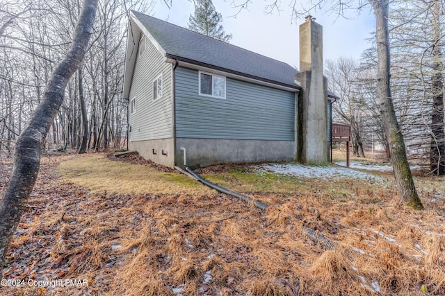 view of home's exterior featuring a shingled roof and a chimney