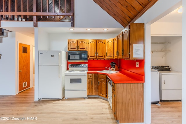 kitchen with brown cabinets, light wood finished floors, washing machine and clothes dryer, a sink, and white appliances