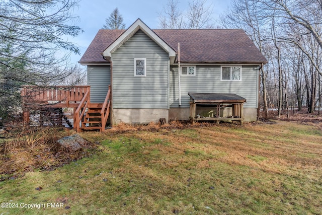 back of house with roof with shingles and a lawn