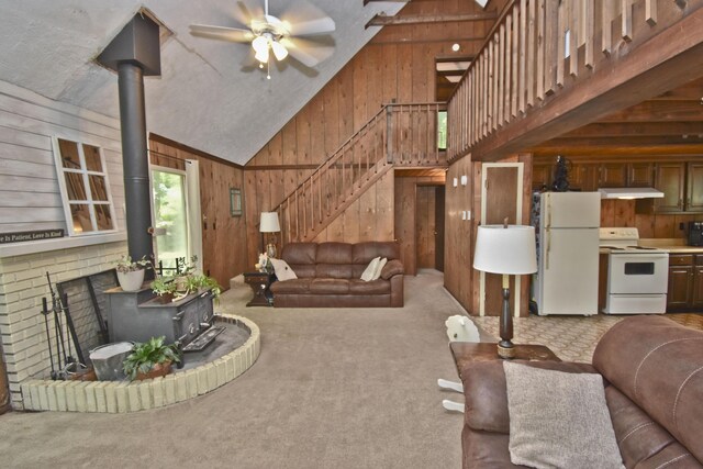 118 Sussex Ct, Bushkill, PA 18324 - living area featuring wood walls, a wood stove, ceiling fan, stairs, and high vaulted ceiling