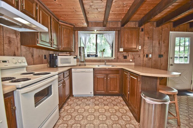 118 Sussex Ct, Bushkill, PA 18324 - kitchen featuring white appliances, under cabinet range hood, a peninsula, a wooden ceiling with exposed beams, and wood walls