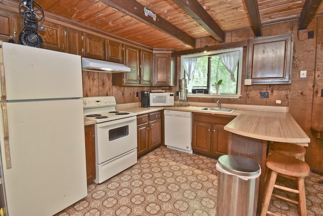 118 Sussex Ct, Bushkill, PA 18324 - kitchen with white appliances, under cabinet range hood, a wood ceiling with exposed beams, wood walls, and light countertops
