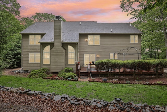 136 Outlook Ct, East Stroudsburg, PA 18302 - back of house at dusk with a wooden deck, a chimney, a yard, and roof with shingles