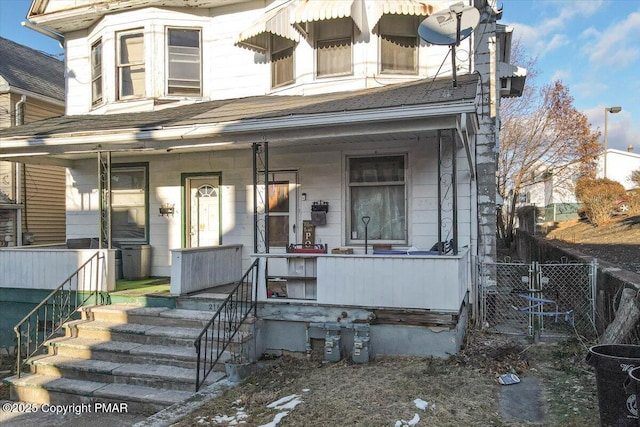 view of front of property with covered porch, fence, and a gate