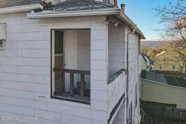 view of side of home with roof with shingles