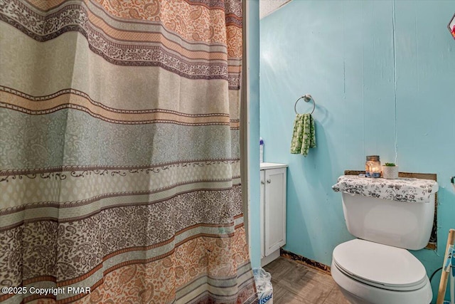 bathroom featuring toilet, curtained shower, baseboards, and vanity