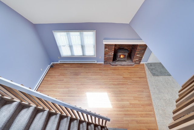 3055 Briarwood Dr, Tobyhanna, PA 18466 - unfurnished living room featuring stairway, a baseboard radiator, light wood-style floors, and a wood stove