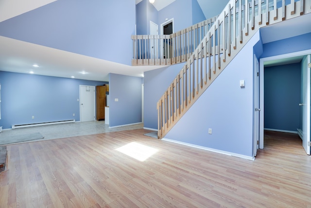3055 Briarwood Dr, Tobyhanna, PA 18466 - unfurnished living room featuring a baseboard heating unit, wood finished floors, stairs, a high ceiling, and recessed lighting