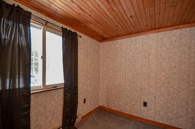 spare room featuring carpet floors, wooden ceiling, and baseboards