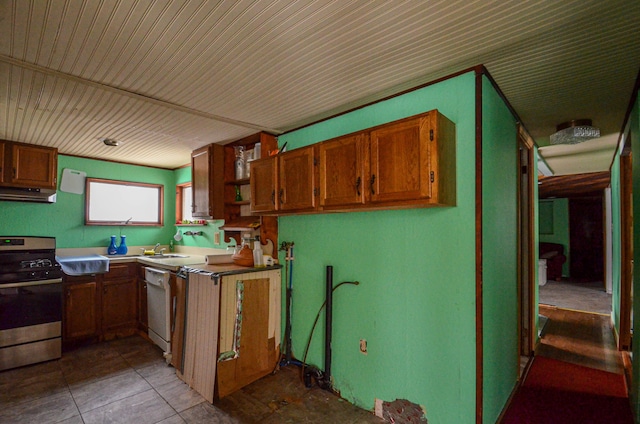 kitchen with under cabinet range hood, a sink, dishwasher, brown cabinetry, and stainless steel range with gas stovetop