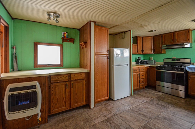 kitchen featuring stainless steel gas stove, freestanding refrigerator, heating unit, light countertops, and under cabinet range hood