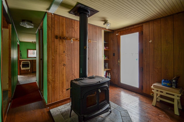 interior space with heating unit, wood walls, and hardwood / wood-style floors