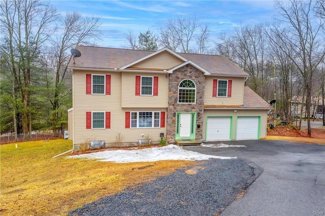 view of front of property with an attached garage, stone siding, a front lawn, and aphalt driveway