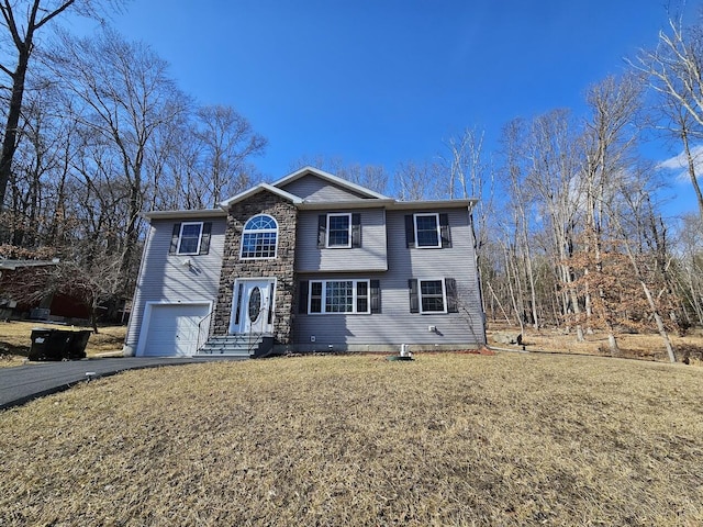 view of front facade with driveway, stone siding, an attached garage, and a front yard