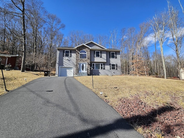 view of front facade featuring a garage, stone siding, aphalt driveway, and a front yard