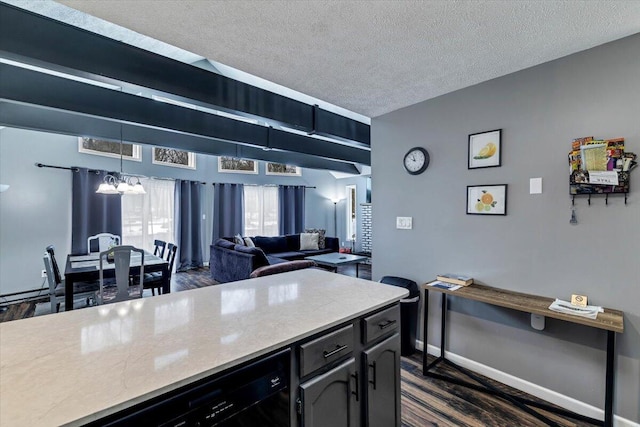 kitchen featuring dark wood-style floors, light countertops, an inviting chandelier, a textured ceiling, and baseboards